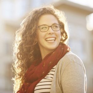 Woman smiling while facing the sun wearing glasses