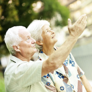 An old couple standing together looking at the sky