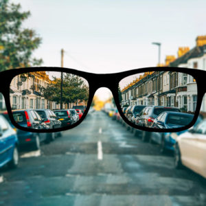 a pair of glasses is held up to the camera lens to show focal difference