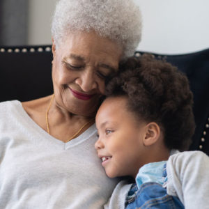 an elderly woman embraces her young grandchild