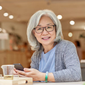 elder woman in glasses using her phone