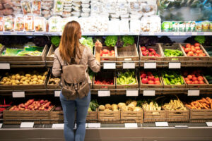 Good looking woman standing in front of vegetable shelves