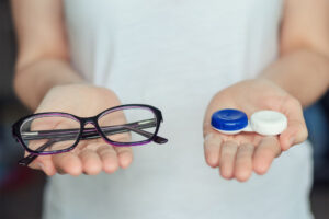 woman hold contact lenses and glasses in hands. concept of choic