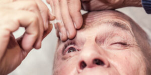 elderly man drip eye drops in eye with medicine dropper glaucoma or cataract therapy concept
